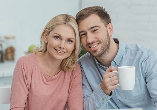 A couple smiling while the man is holding a mug